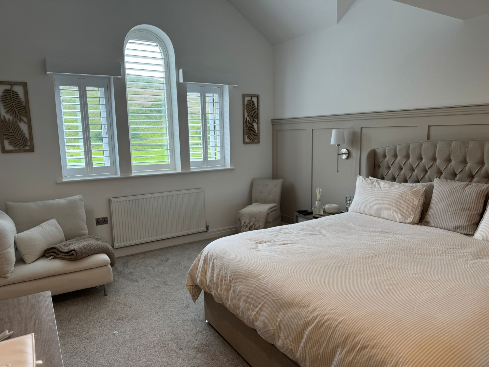 White shaped shutters fitted to a triple bedroom window with a central arched top section
