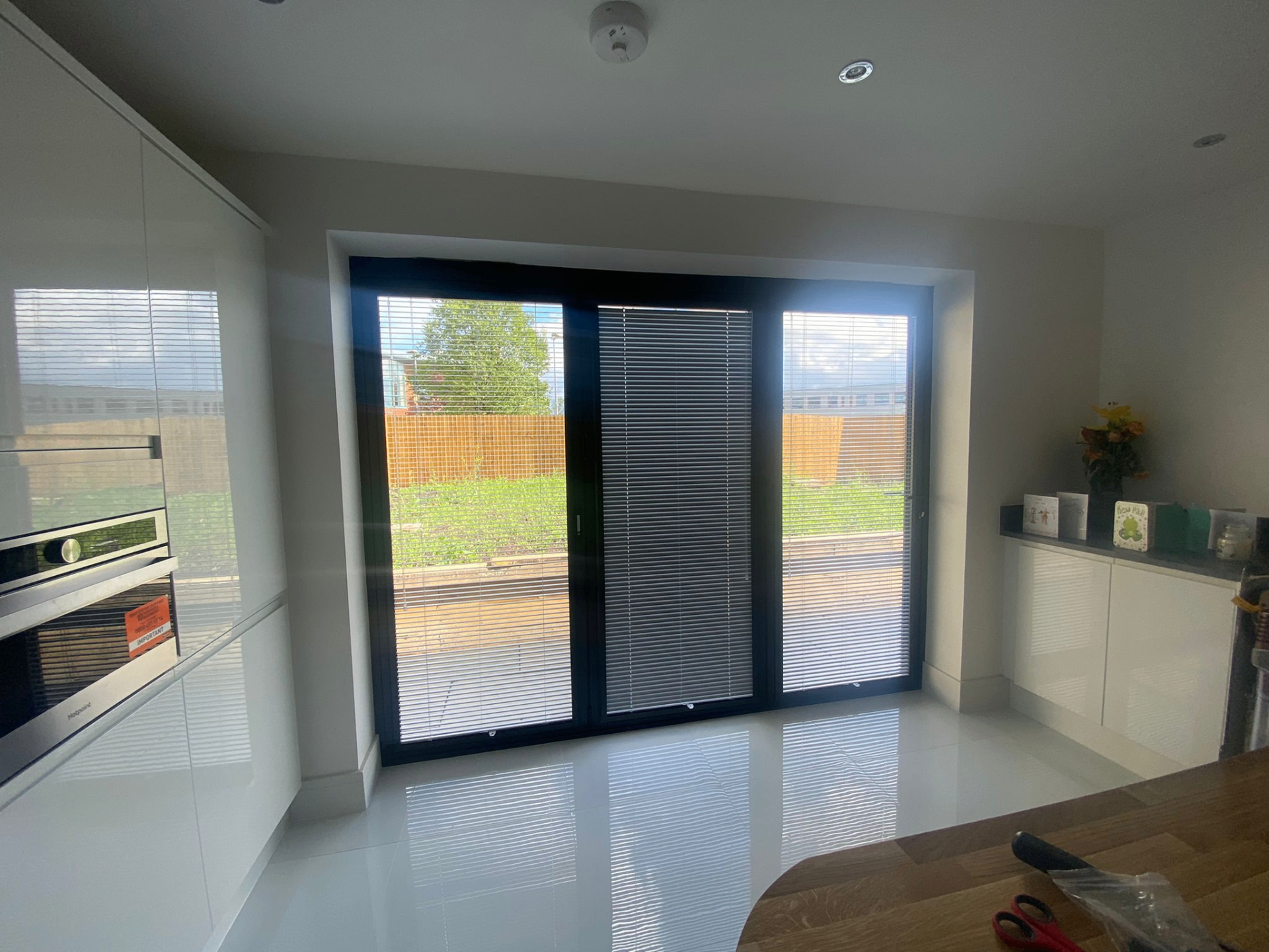 Anthracite Perfect Fit pleated blinds fitted directly to patio door frames in a modern kitchen