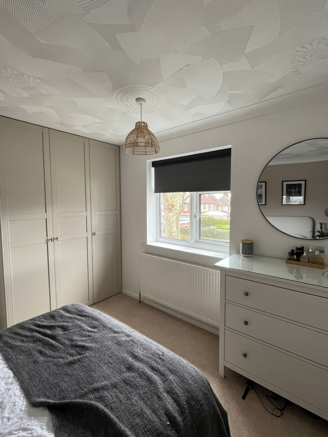 Charcoal blackout roller blind fitted in a bright bedroom
