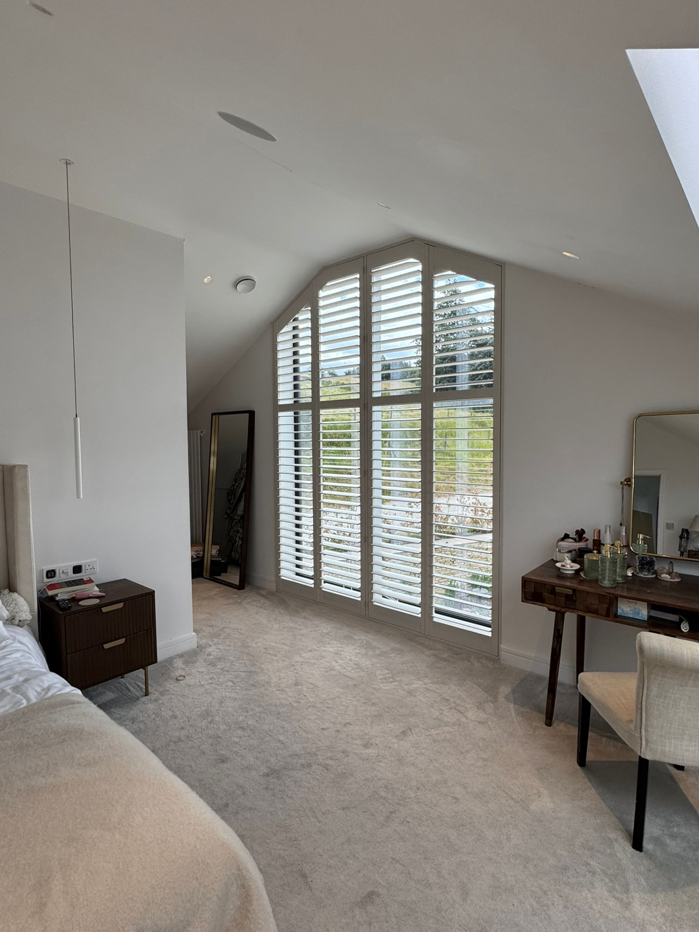 Side angle of a loft bedroom showing shaped shutters fitted within an angled feature window
