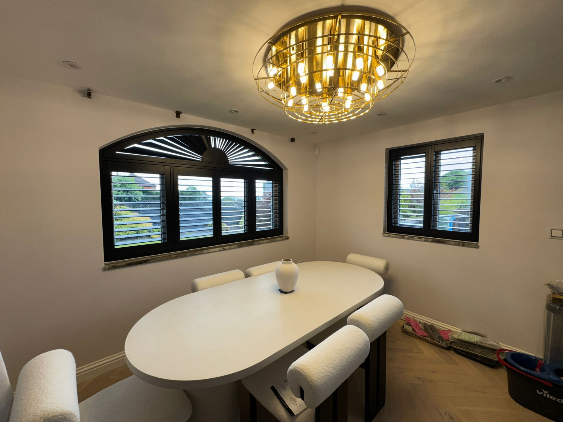 Black shaped shutters fitted across an arched dining-room window with matching side windows