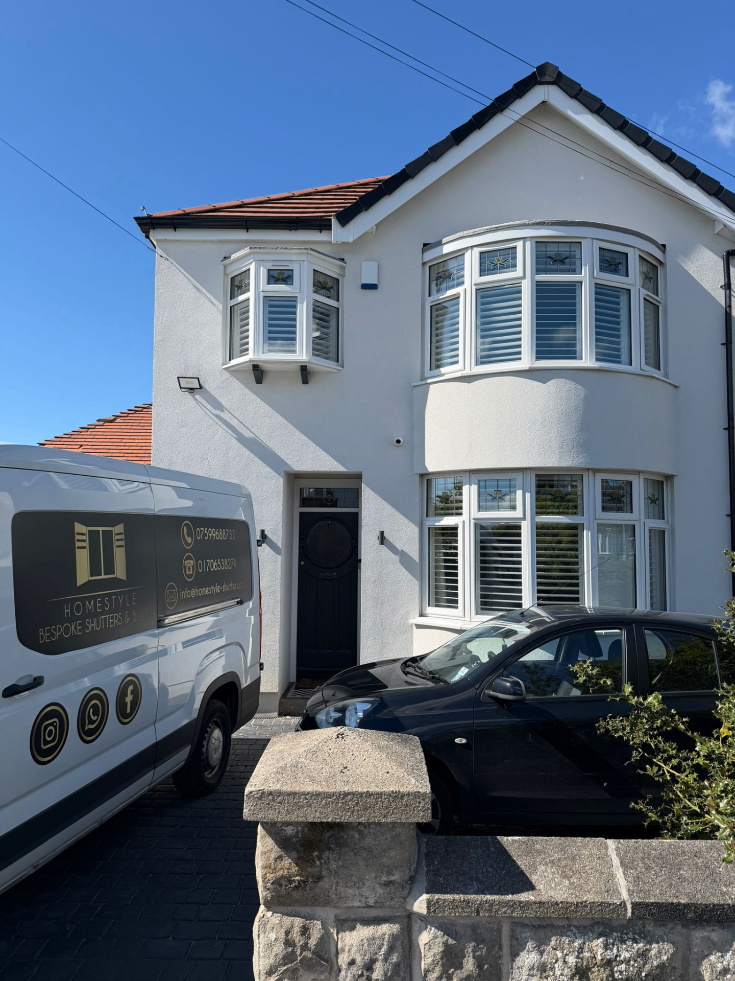 Exterior of a white detached home with bay windows fitted with plantation shutters