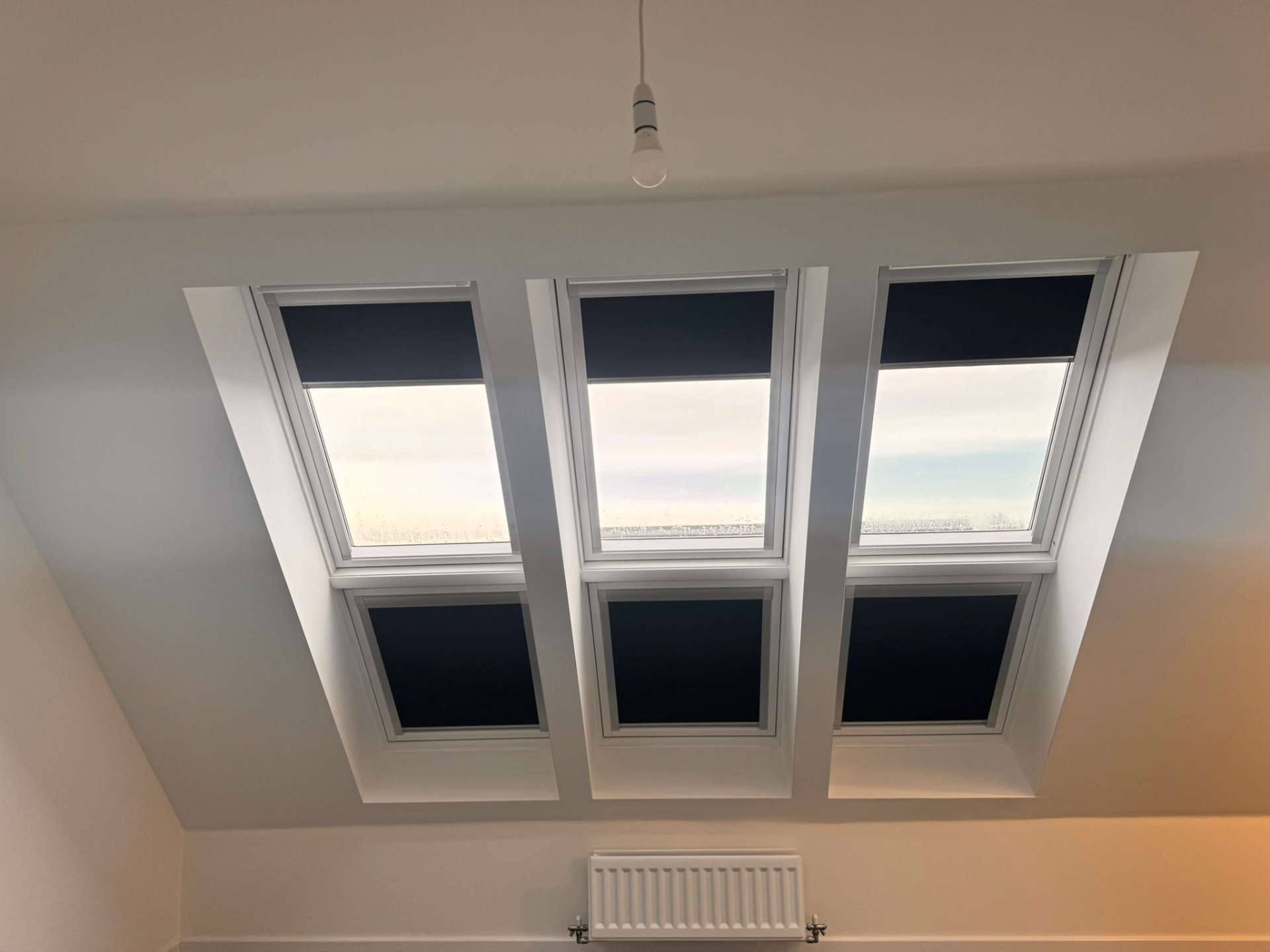 Three fitted Velux blackout blinds shown partly open across loft roof windows