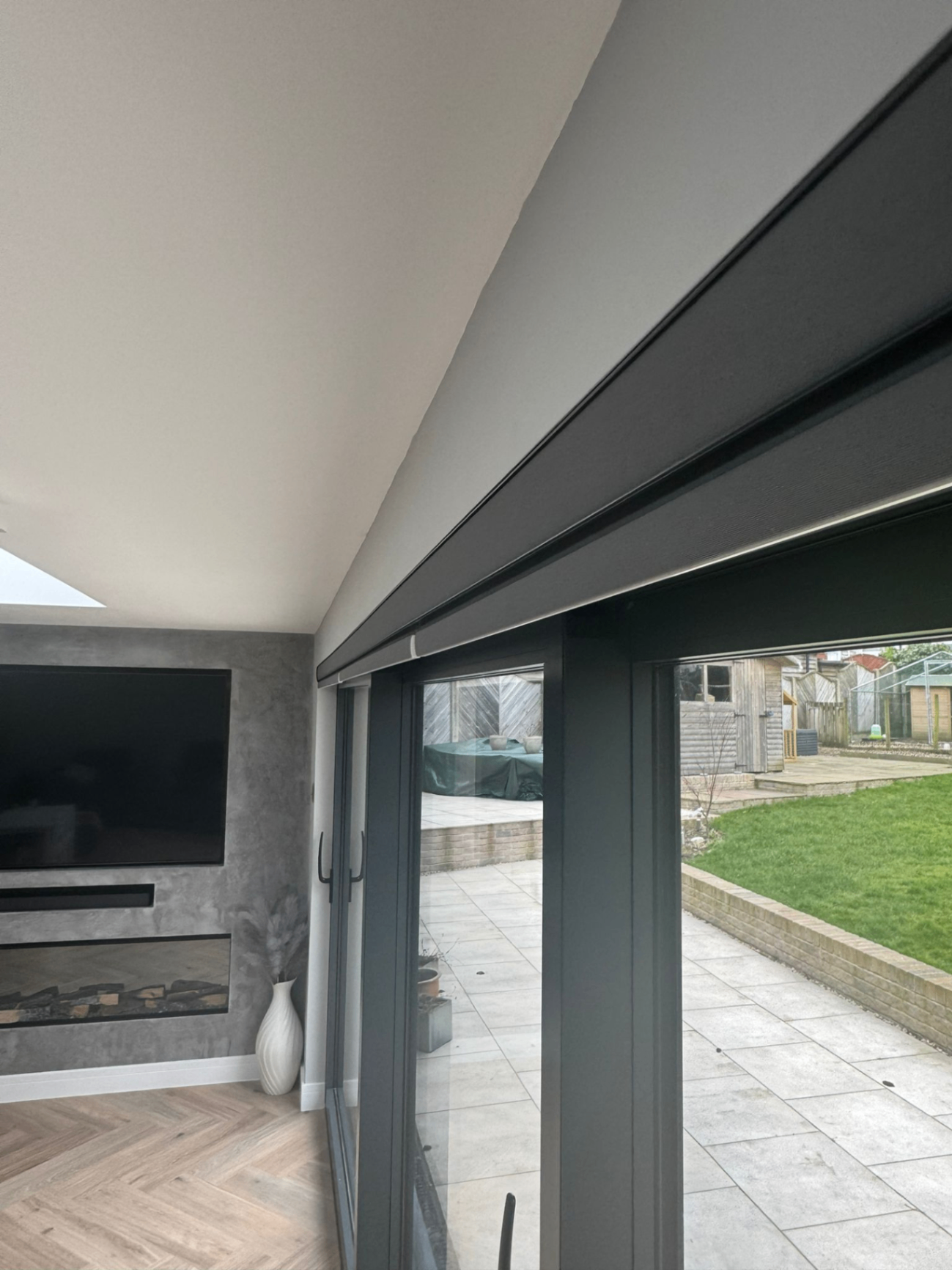 Anthracite motorised roller blinds fitted over large sliding patio doors in a living room