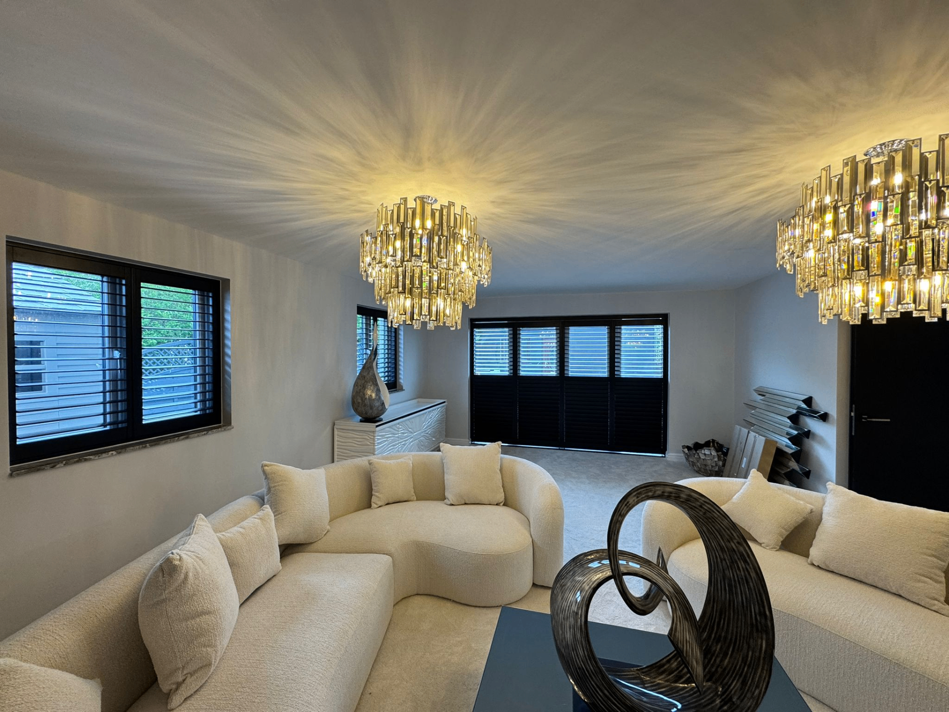 Dark bifold tracked shutters drawn across a large opening in a modern living room