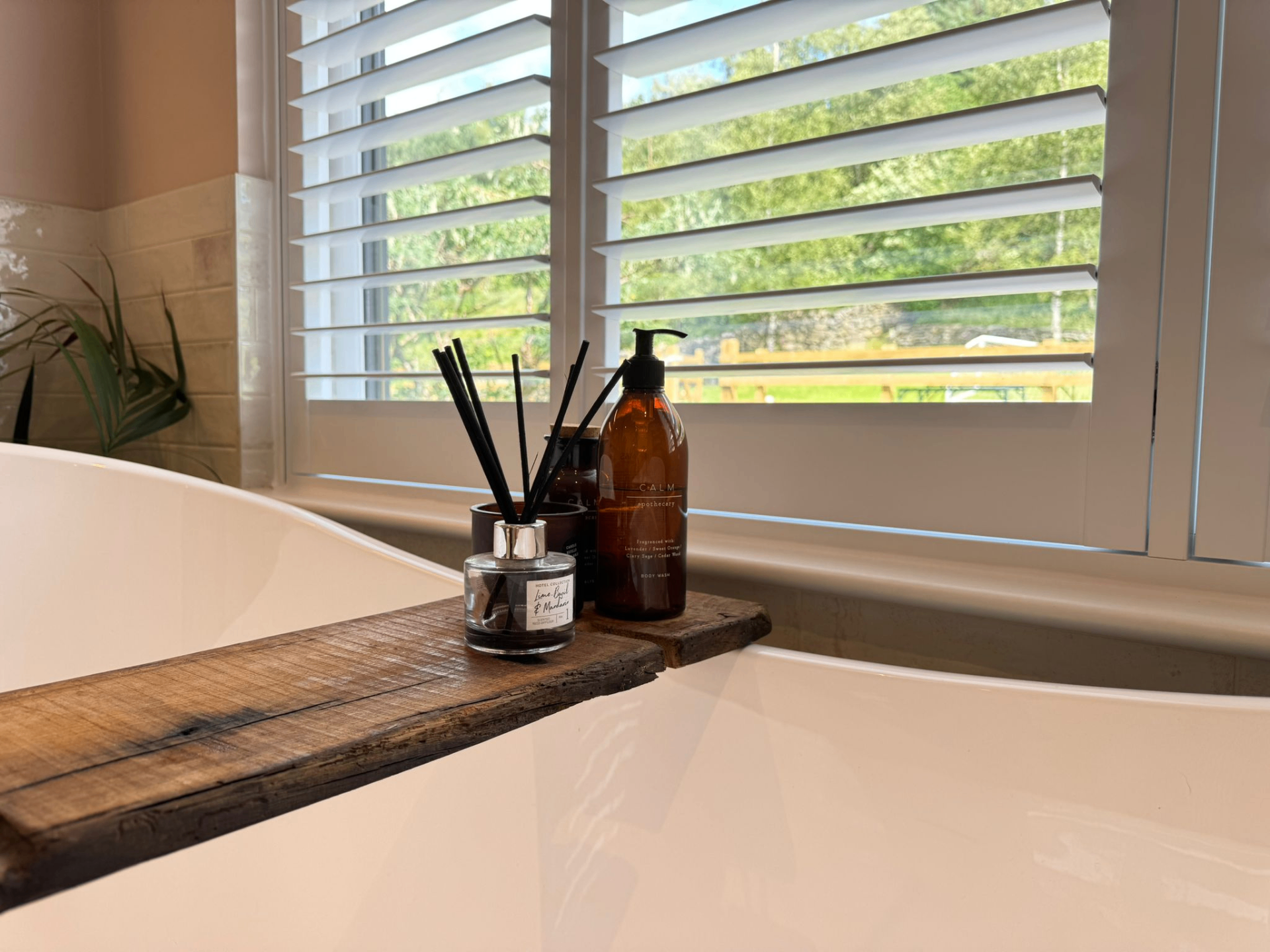 Close-up of waterproof PVC shutters above a bath with bathroom accessories in the foreground