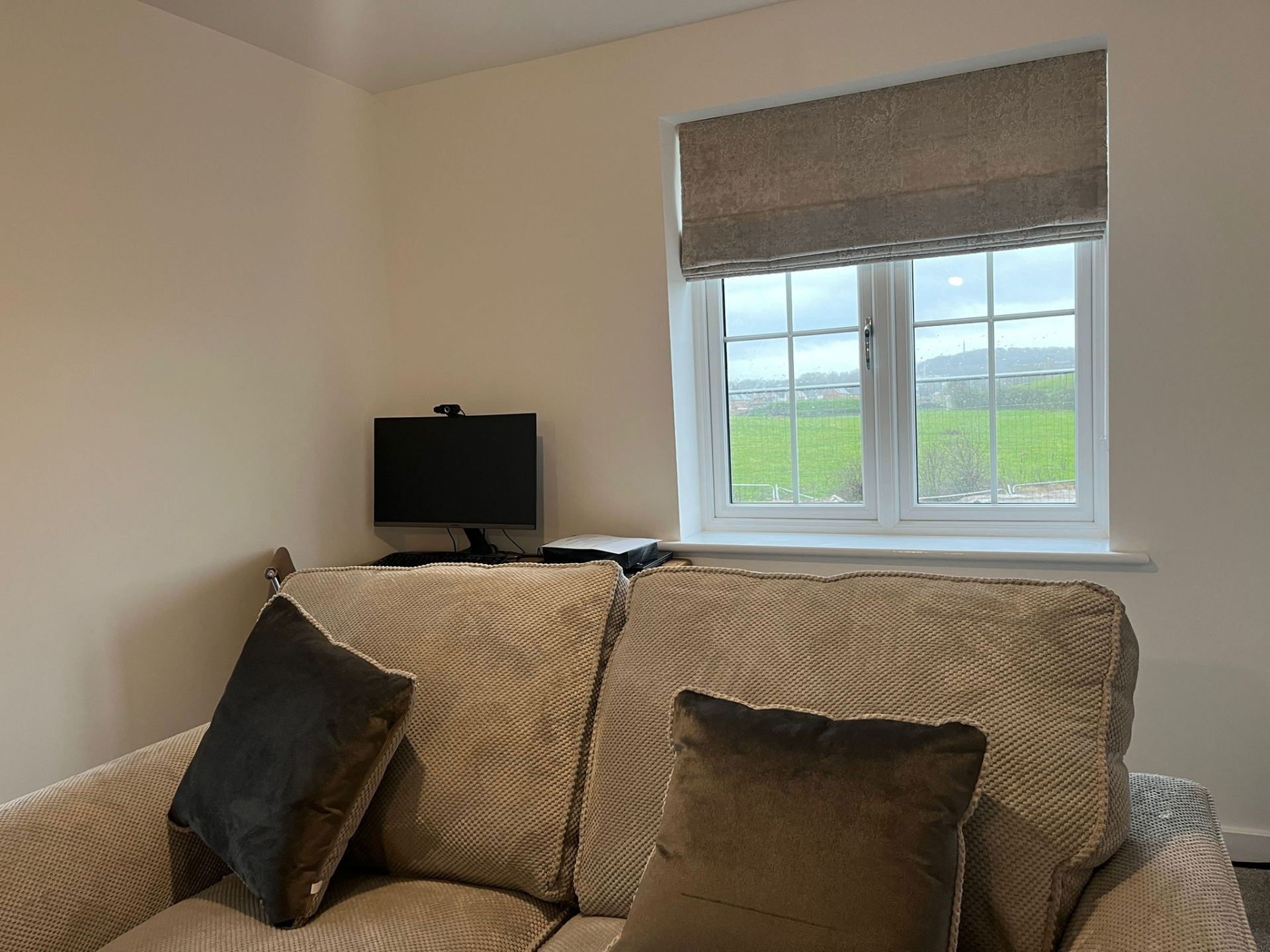 Single taupe Roman blind above a sofa in a lounge