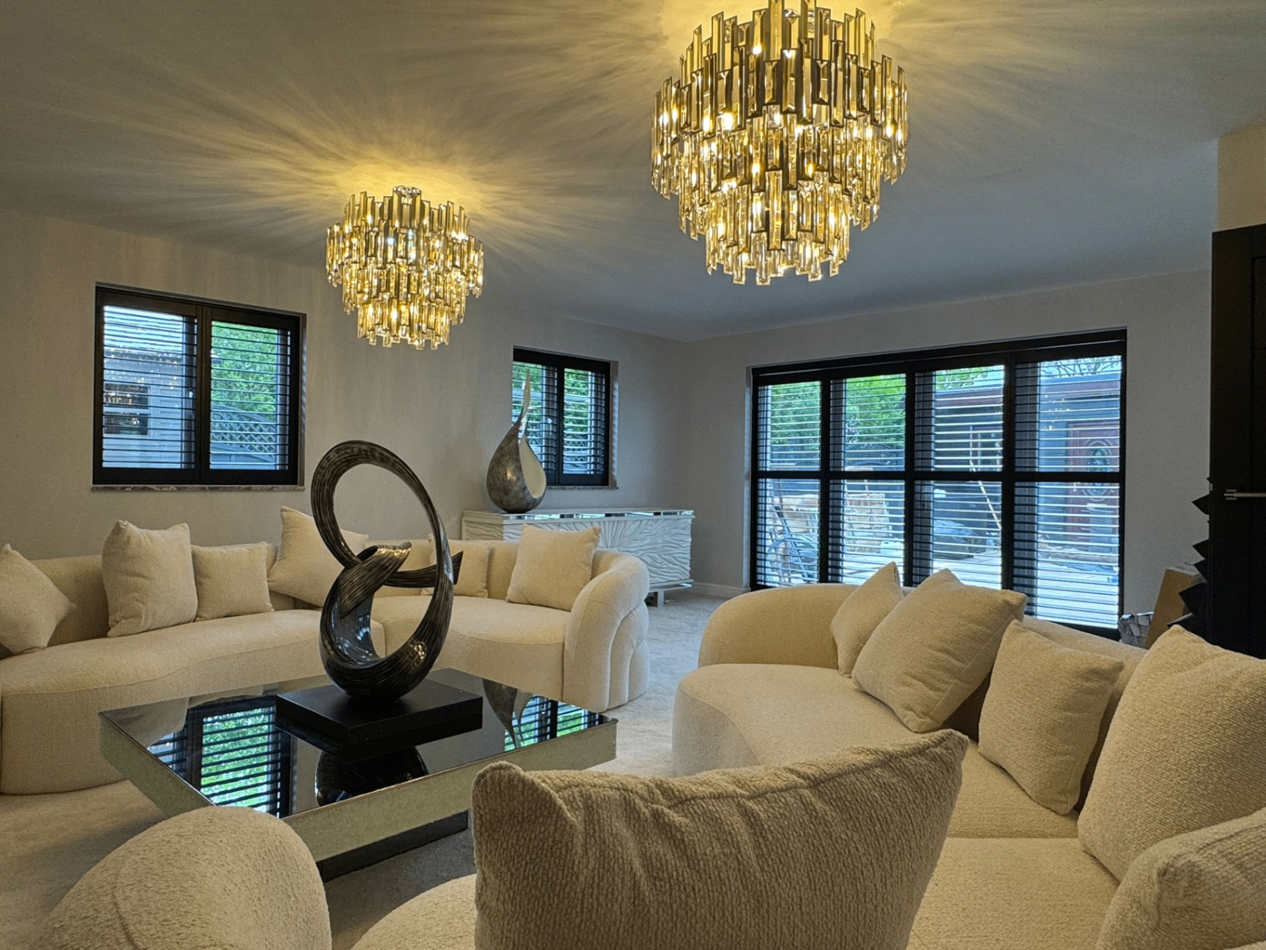 Dark bifold tracked shutters fitted across wide glazed doors in a luxury lounge