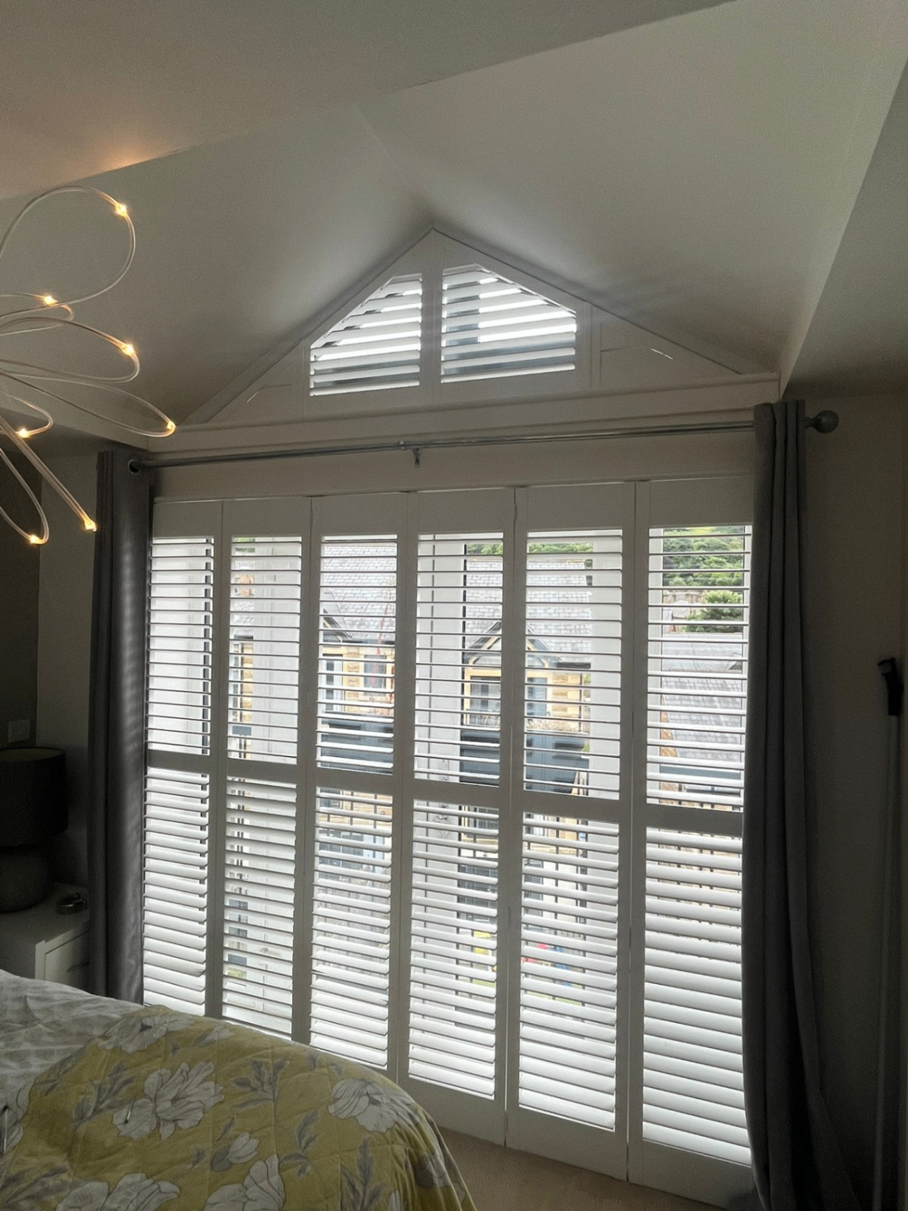 White shaped shutters installed over bedroom doors with a triangular gable section above